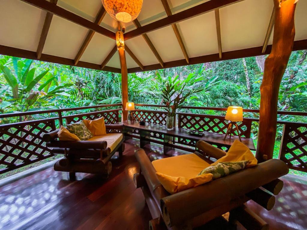 a living room with chairs and a balcony with trees at Finca Chica Lodge & Villas in Puerto Viejo