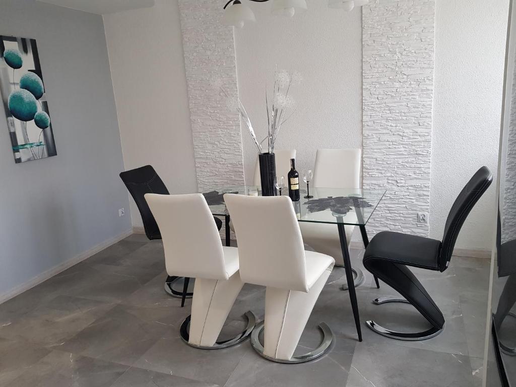 a dining room with a glass table and white chairs at Dmuchawiec in Jelenia Góra