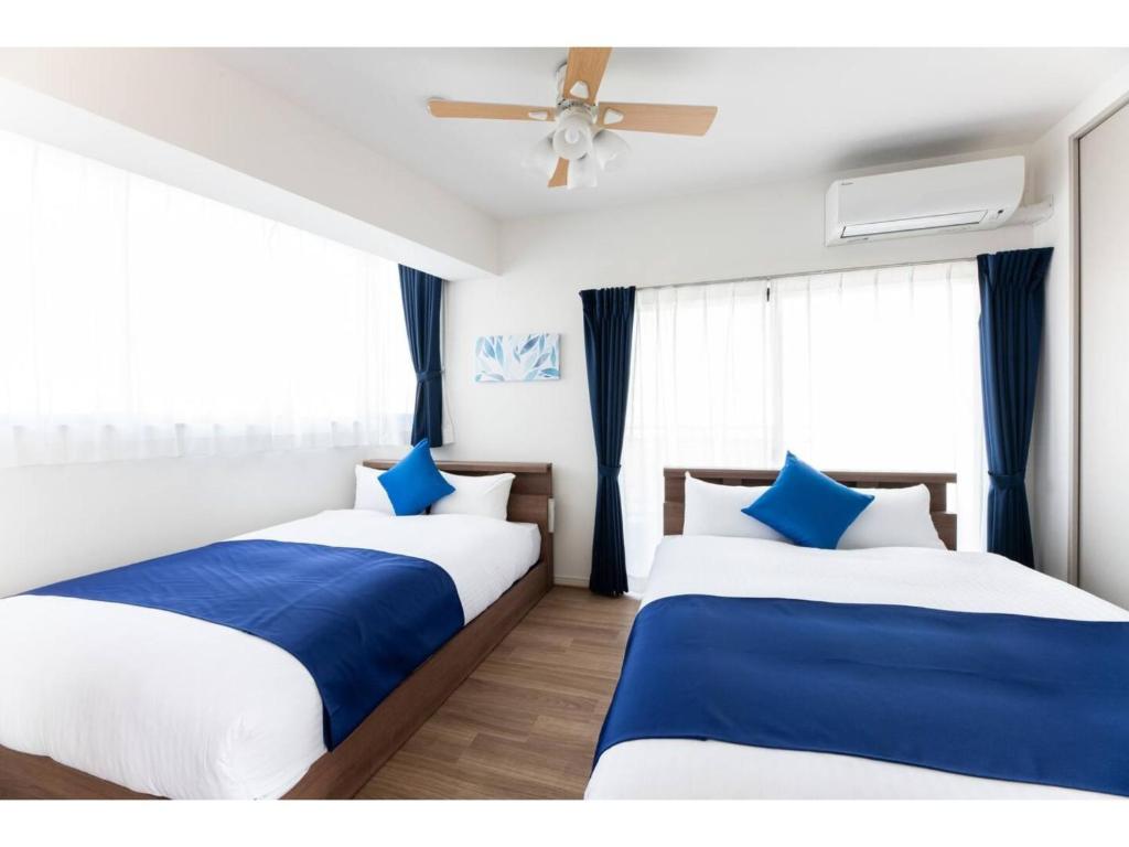 Grand Inn Canalside - Vacation STAY 89664 في فوكوكا: سريرين في غرفة باللون الأزرق والأبيض