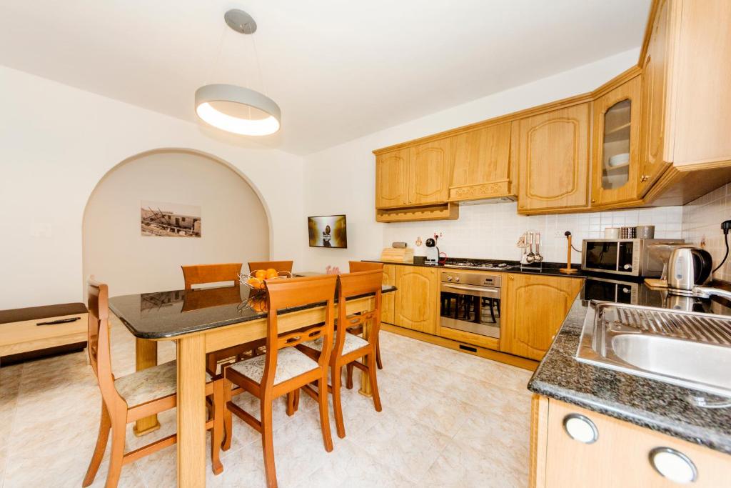 una cocina con armarios de madera, mesa y sillas en Central 3 Bedroom Entire Apartment Msida en Msida
