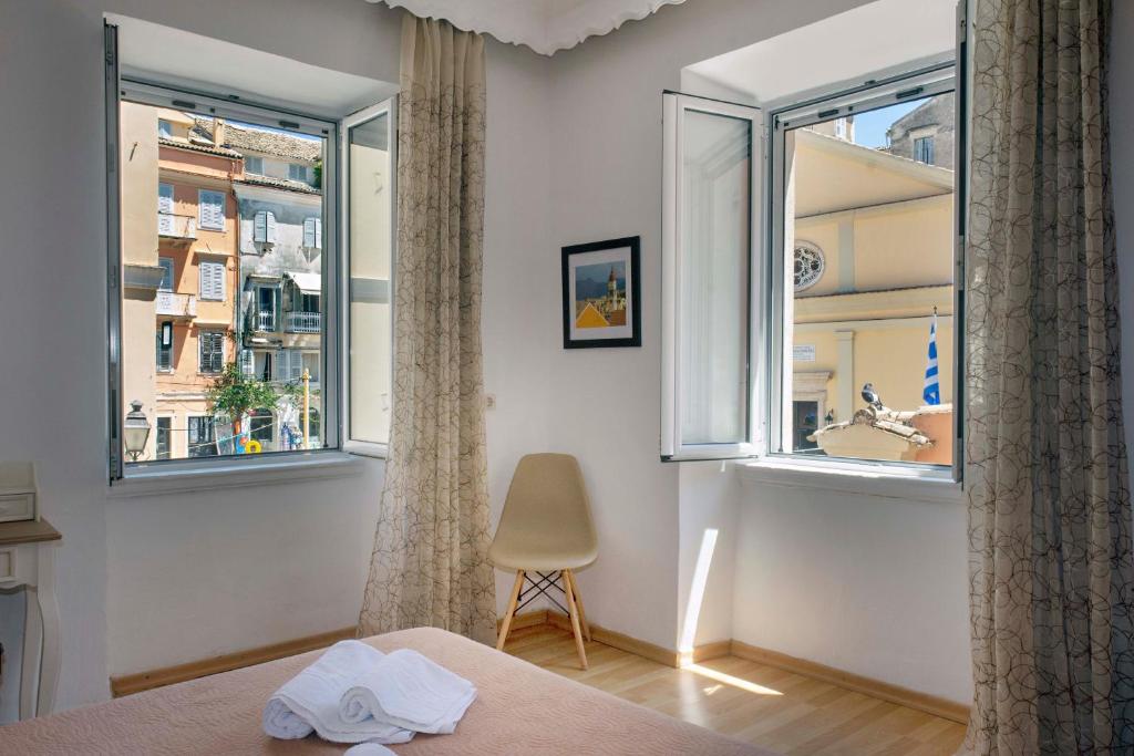 コルフ・タウンにあるTheodora's old Corfu homeのベッドルーム1室(窓2つ、椅子1脚、ベッド1台付)