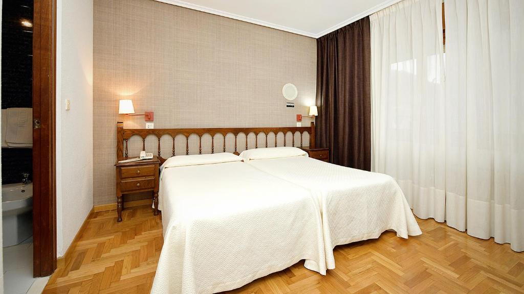 sypialnia z białym łóżkiem i drewnianą podłogą w obiekcie Hotel El Molinón w mieście Cangas del Narcea