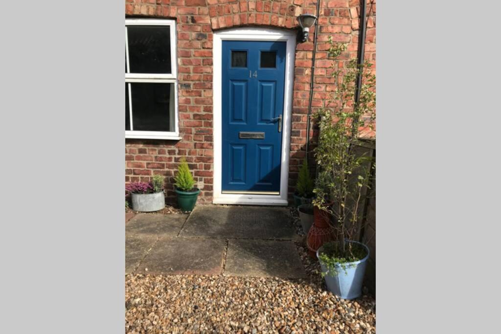 una puerta azul en una casa de ladrillo con macetas en Attractive 2 bed cottage in Hempton Fakenham, en Fakenham