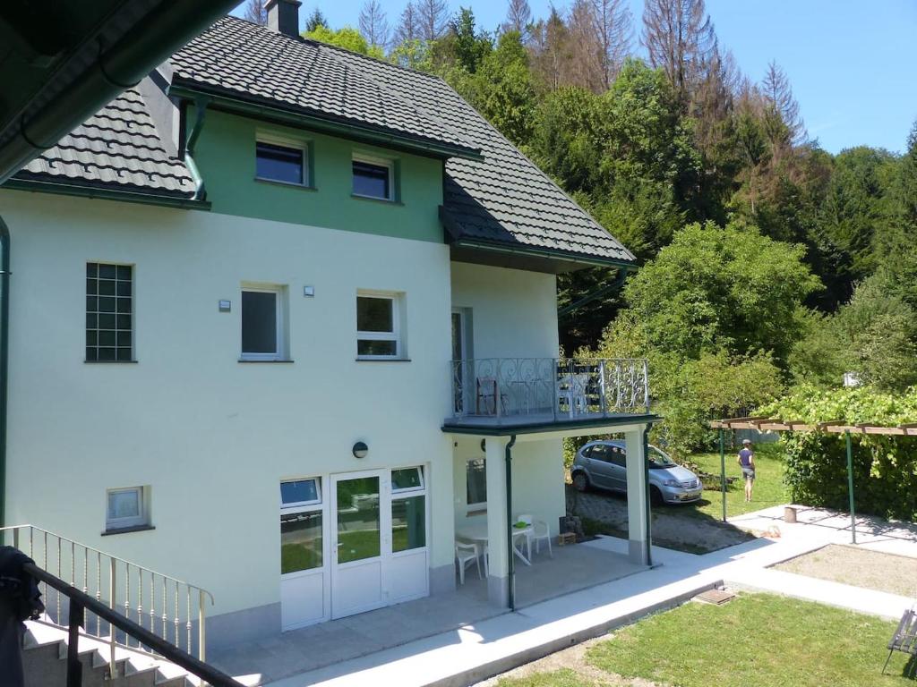 uma casa branca com uma varanda e um carro em Riverside garden apartment Three Springs Tri Zvira em Plešce