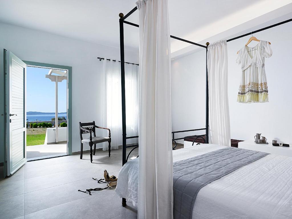 a white bedroom with a bed and a balcony at Santa Maria Luxury Suites & Spa in Adamas
