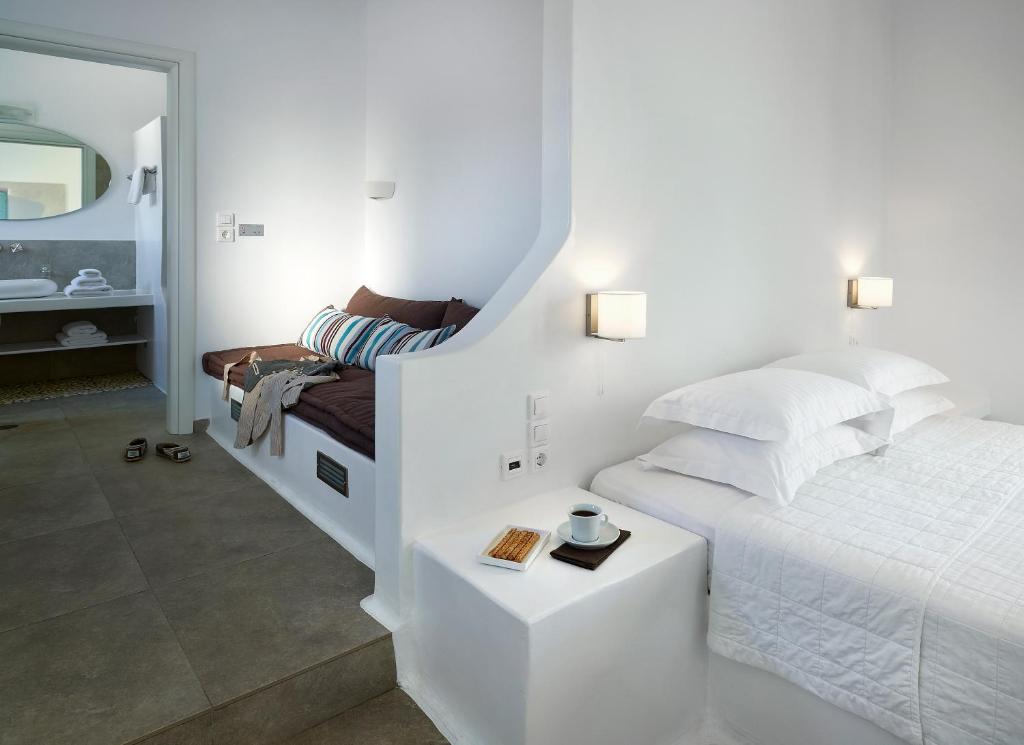 a white bedroom with a bed and a mirror at Santa Maria Luxury Suites & Spa in Adamas