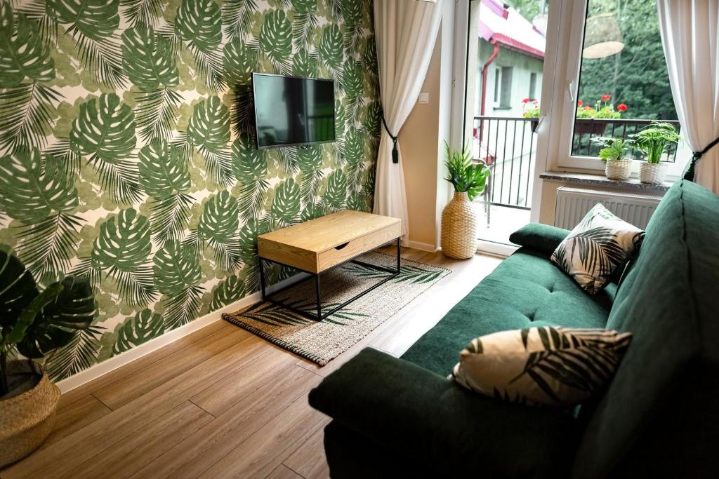 a living room with a green couch and a tv at Apartamenty Willove Wzgórze in Duszniki Zdrój