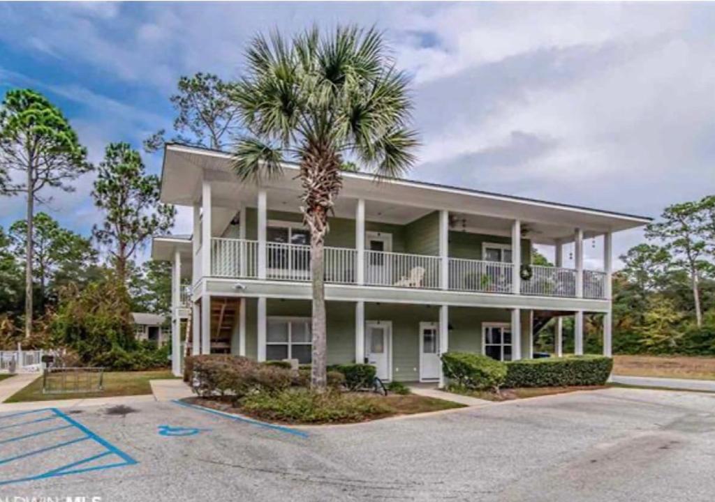 a large white house with a palm tree in front of it at Condo w Pool near beaches, dining, shopping, etc in Gulf Shores