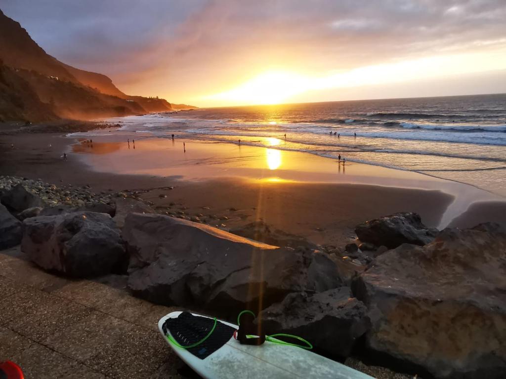 a surfboard on the beach with the sunset in the background at HolidaynorthTenerife Exotic Apartament in Los Realejos