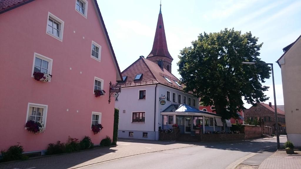 een roze gebouw met een toren naast een kerk bij Gasthof Endres in Allersberg