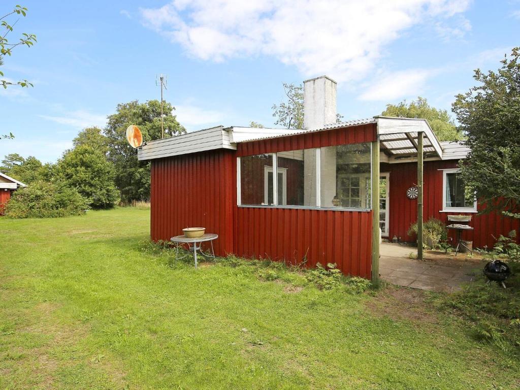 un cobertizo rojo con una mesa delante en 6 person holiday home in G rlev, en Gørlev