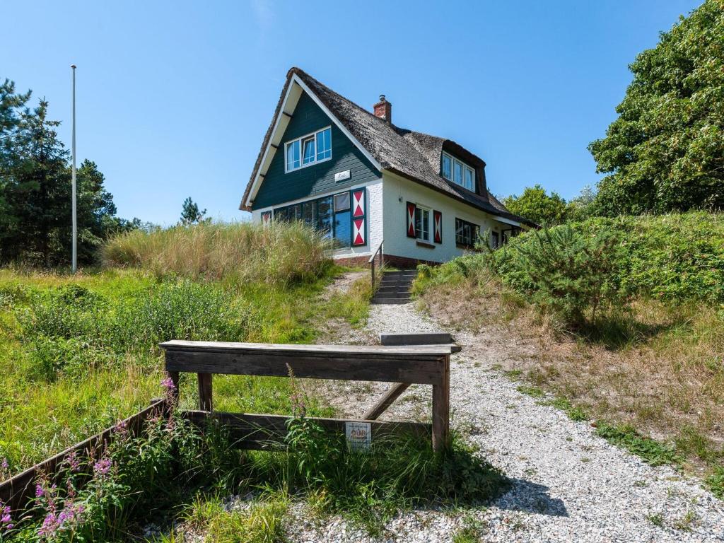 una casa en una colina con un banco delante en Beautiful dune villa with thatched roof on Ameland en Buren