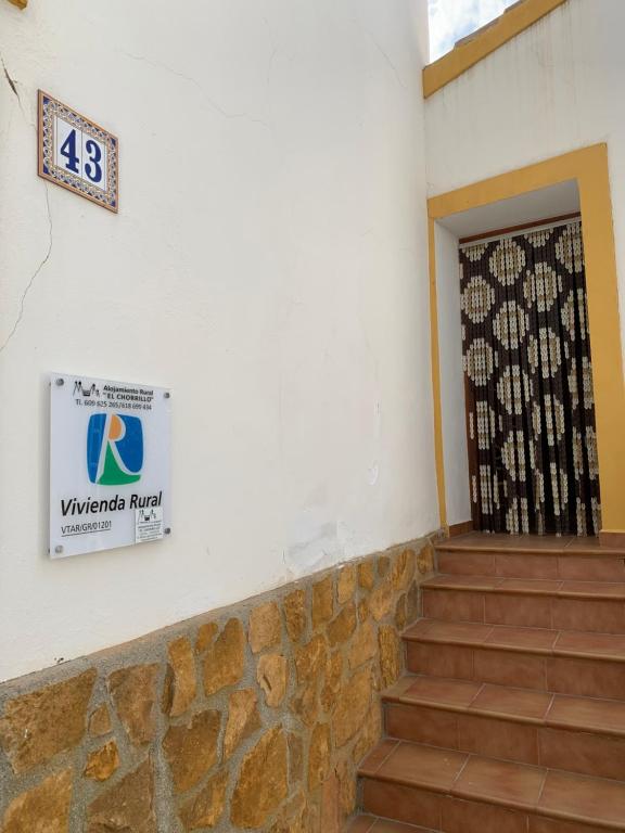 une porte menant à un bâtiment avec un panneau sur le mur dans l'établissement Habitación Rural El Chorrillo, à Castril