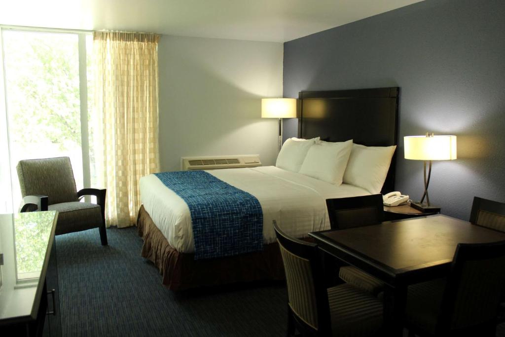 a hotel room with a bed and a desk and a table at Travelodge by Wyndham Water's Edge Hotel - Racine in Racine