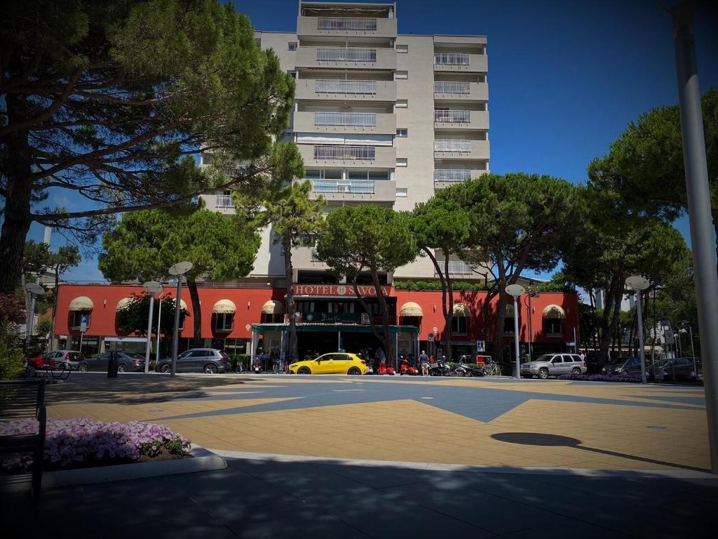 un gran edificio con un coche amarillo frente a una calle en Hotel Savoia, en Lignano Sabbiadoro