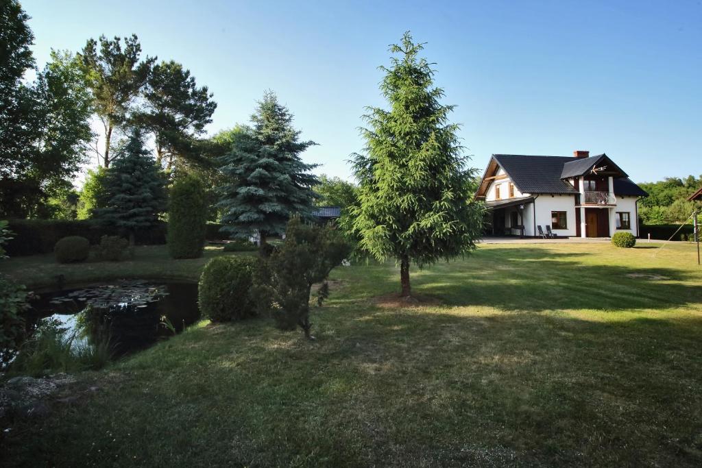 ein Haus mit einem Teich und Bäumen im Hof in der Unterkunft Dom w Lubiatowie całoroczny in Lubiatowo