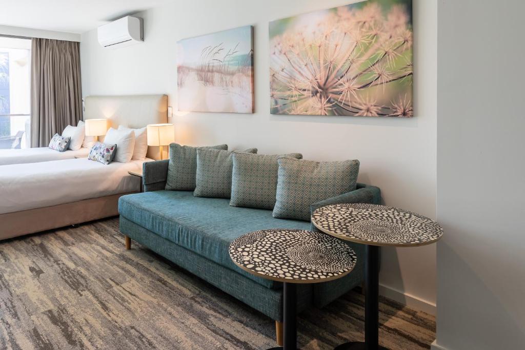 a living room with a couch and two tables at Narrabeen Sands Hotel by Nightcap Plus in Narrabeen