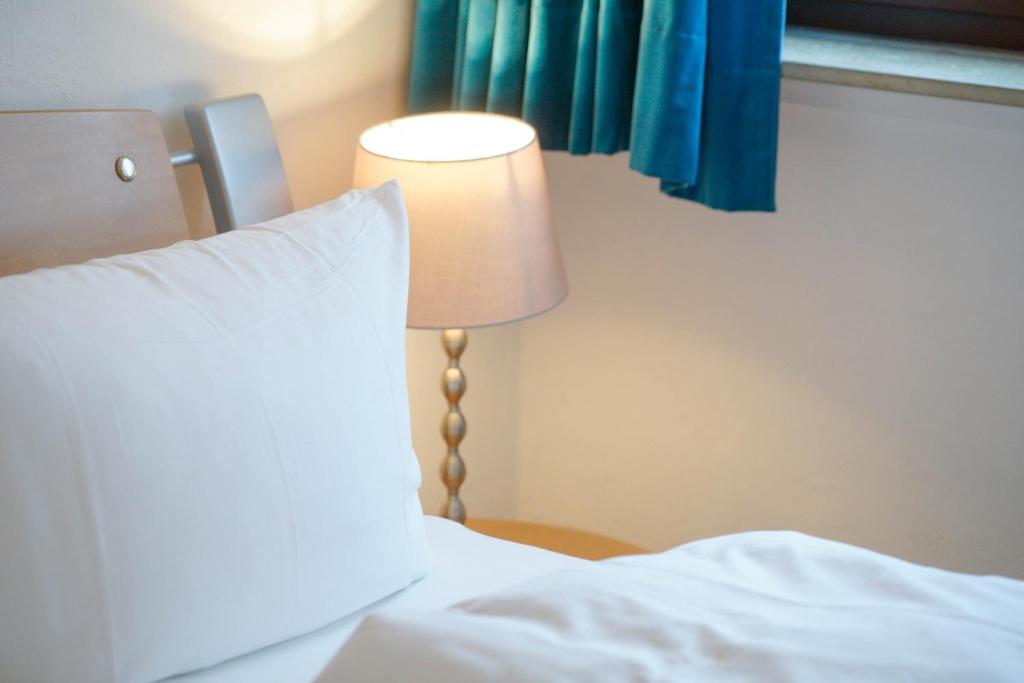 ein Bett mit einem weißen Kissen und einer Lampe in der Unterkunft Dünenblick 4 Personen Strandnähe ruhig gelegen in Westerland