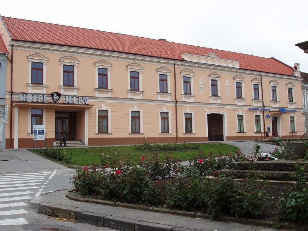 a large building with a garden in front of it at Hotel Jelen in Hlohovec