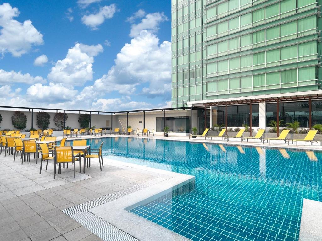 een zwembad met stoelen en tafels en een gebouw bij St Giles Boulevard in Kuala Lumpur