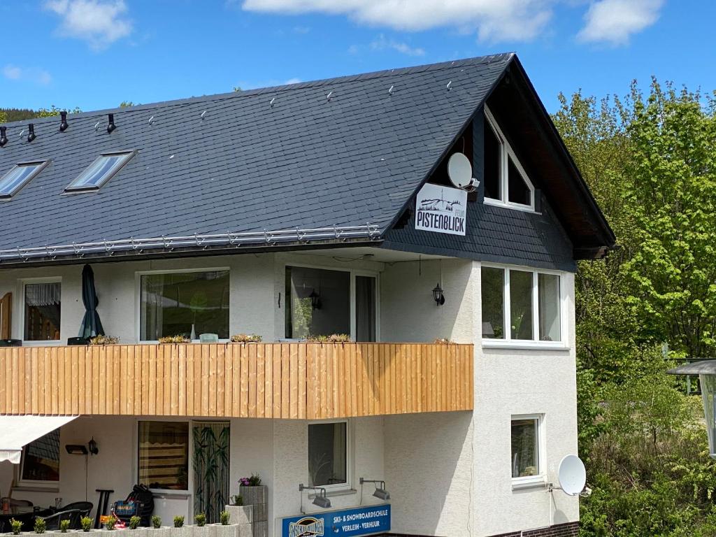 a house with a black roof and a balcony at Pistenblick in Willingen
