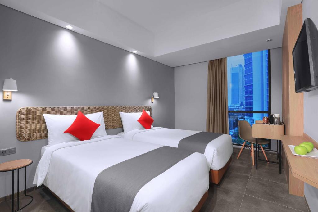 een hotelkamer met een groot bed met rode kussens bij Neo Hotel Puri Indah in Jakarta
