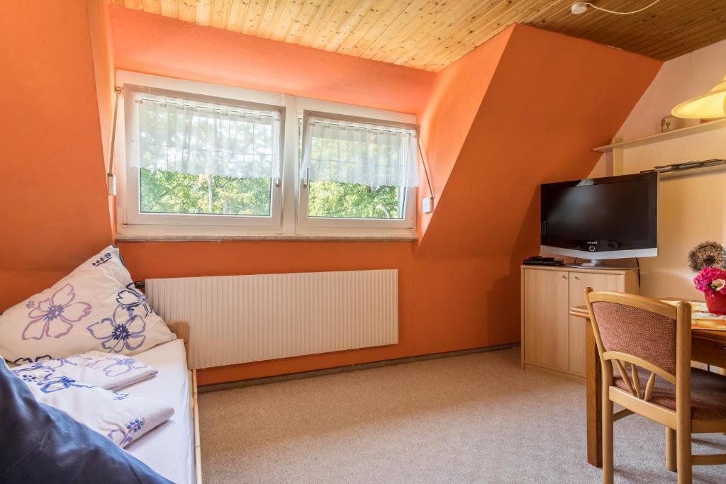 Zimmer mit orangefarbenen Wänden, einem TV und einem Tisch in der Unterkunft Haus Bea in Lindau