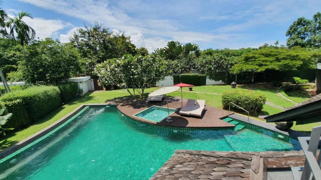a swimming pool with a table and chairs in a yard at Azaya Luxury 4 Bedrooms Pool Villa in Chiang Mai