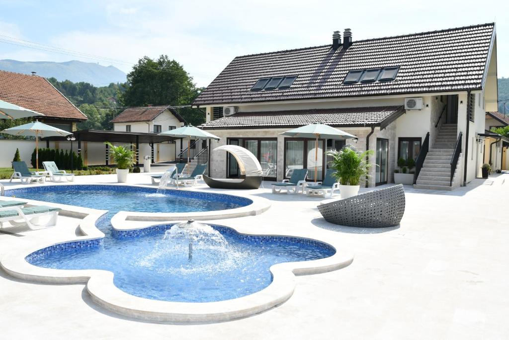 a pool with a fountain in front of a house at Villa Magic Sa in Uzdojnice