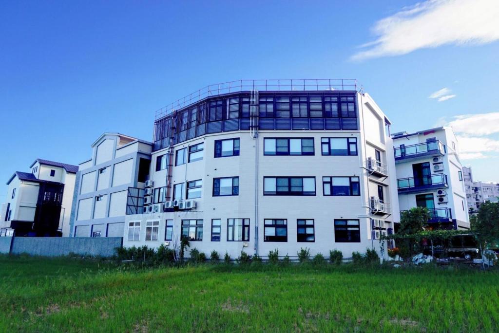 a large white building with a grass field in front of it at Autumn Fountain Homestay in Jiaoxi