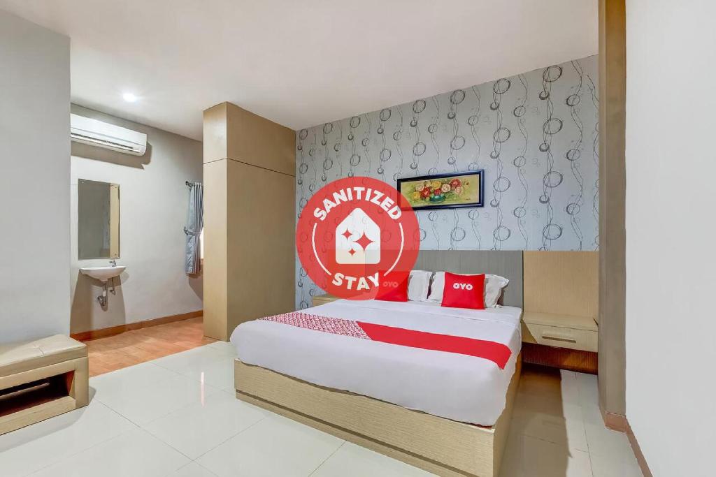 1 dormitorio con 1 cama grande y un letrero rojo en la pared en OYO Flagship 3726 Tembok Batu Residence, en Yogyakarta