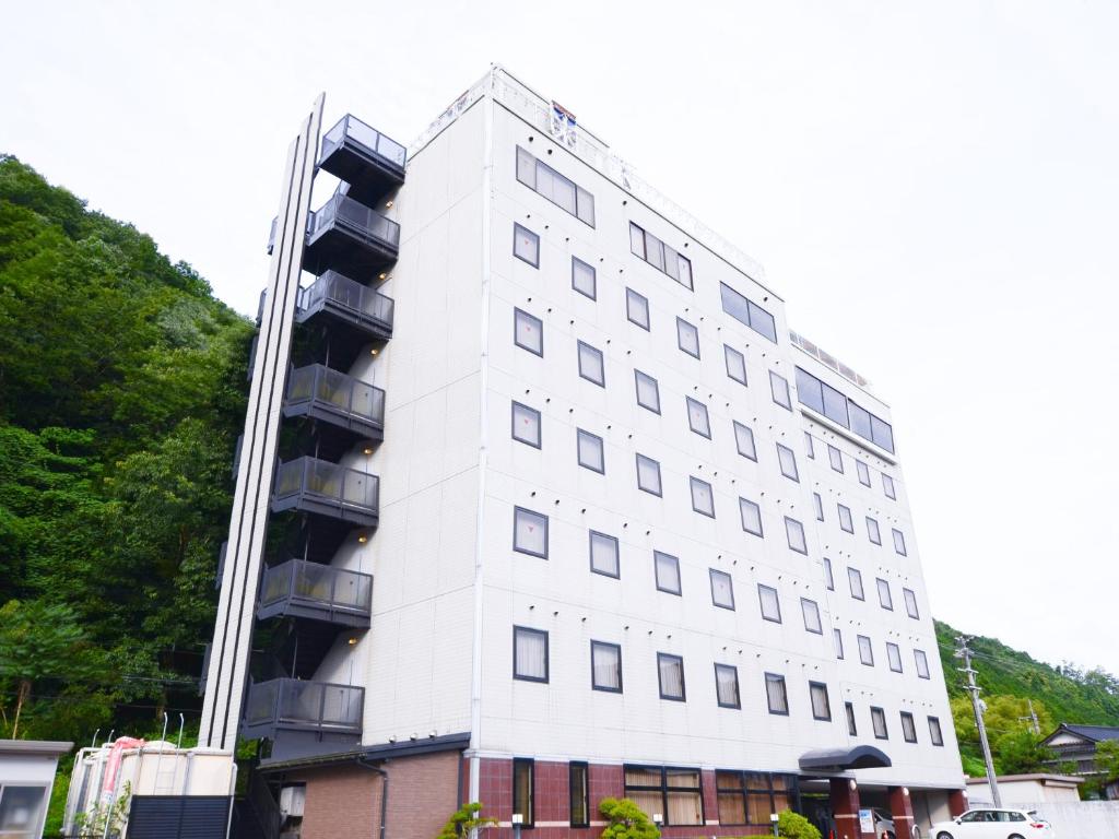 Biały budynek z balkonami na boku w obiekcie Hotel Areaone Wadayama w mieście Asago