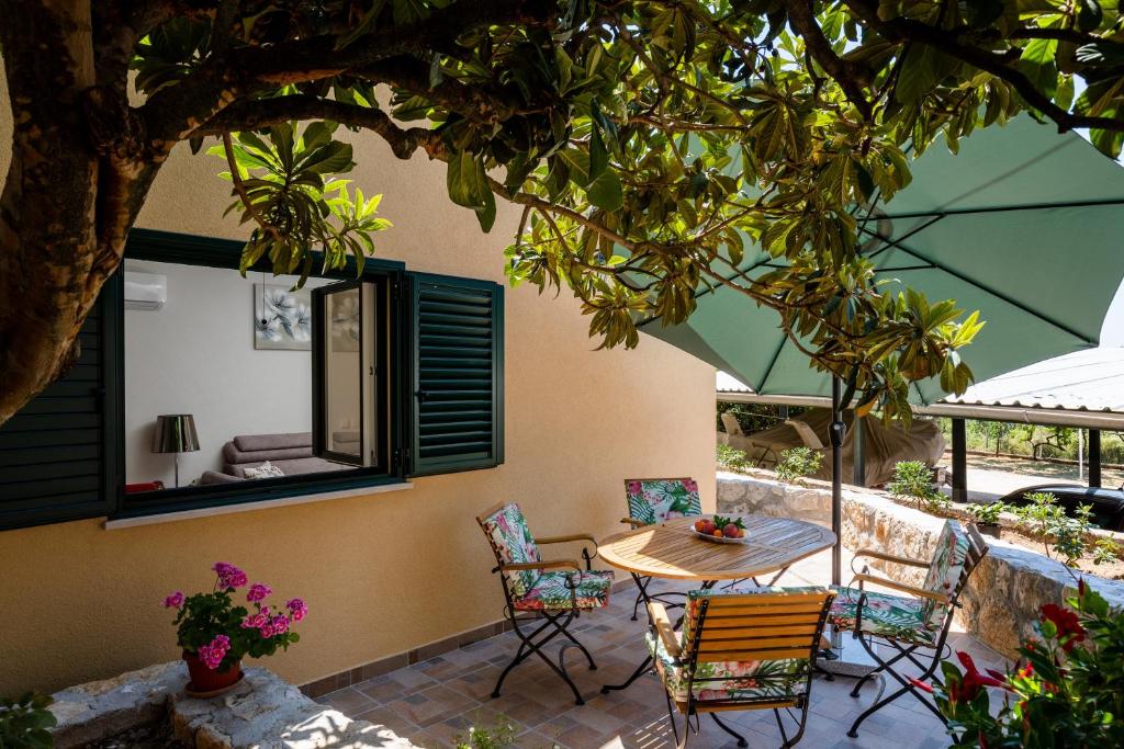 un patio con mesa y sillas bajo un árbol en Apartment Pod Nespolom, en Trsteno