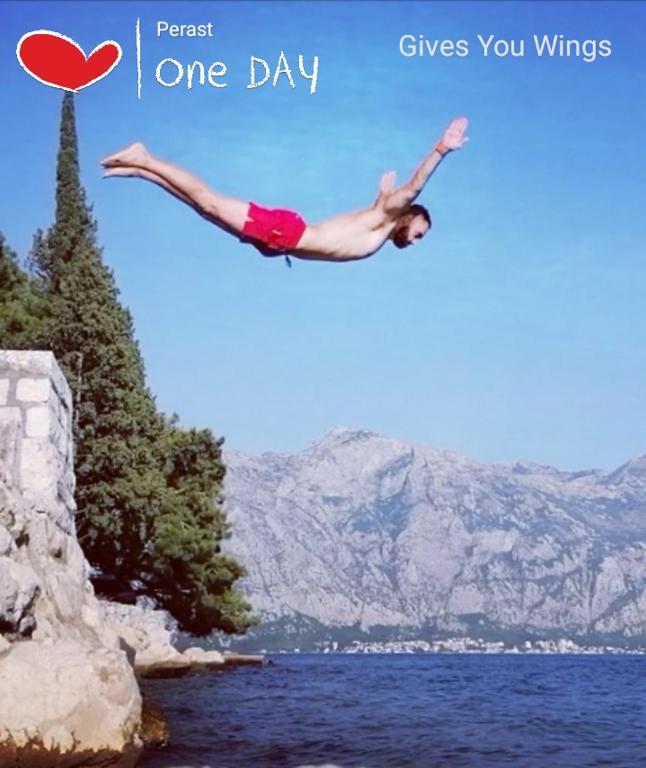 a woman doing a flip in the air over a body of water at Apartment Mediterraneo Blue Sky in Perast
