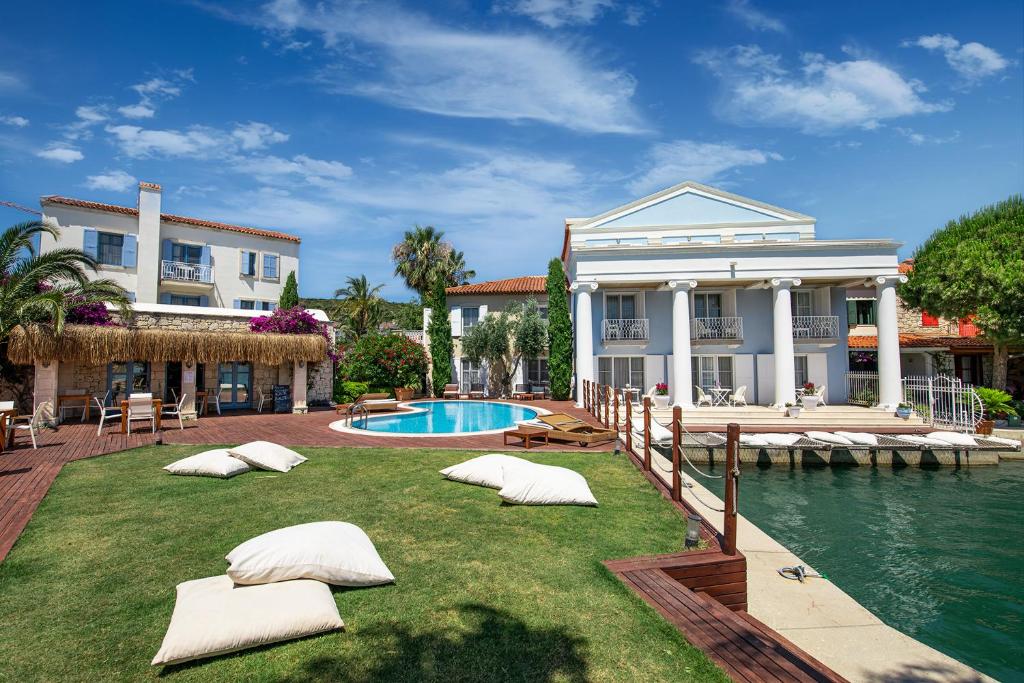 una casa con almohadas en el césped junto a una piscina en Port Alacati Hotel, en Alacati