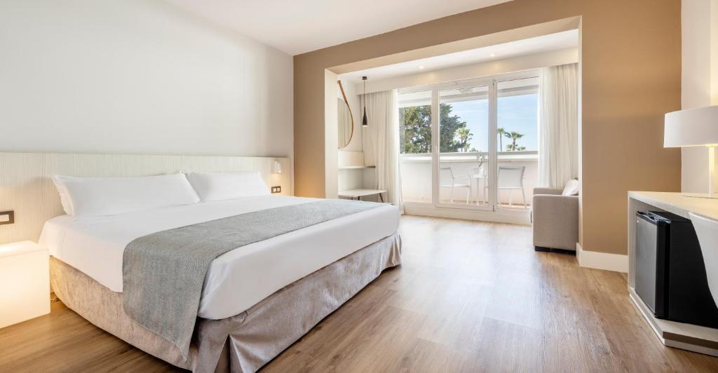 a bedroom with a large bed and a large window at Ilunion Islantilla in Islantilla