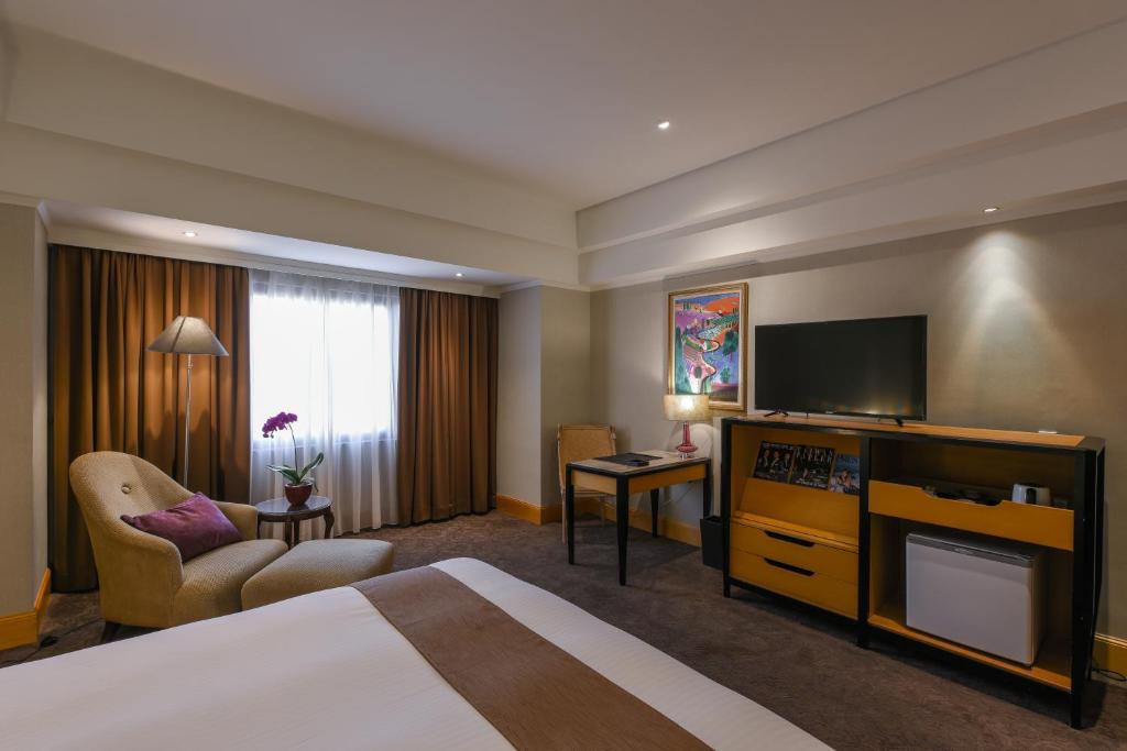 a hotel room with a bed and a flat screen tv at THE LEES Hotel in Kaohsiung