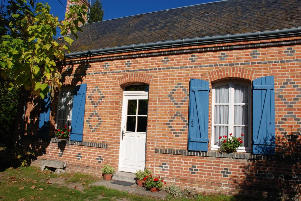 una casa de ladrillo con persianas azules y una puerta blanca en La Renardie, en La Ferté-Imbault