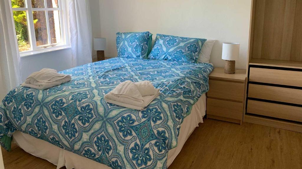 a bedroom with a blue and white bed with towels on it at Shippen Cottage - Perfect for Couples or Families in Sidmouth