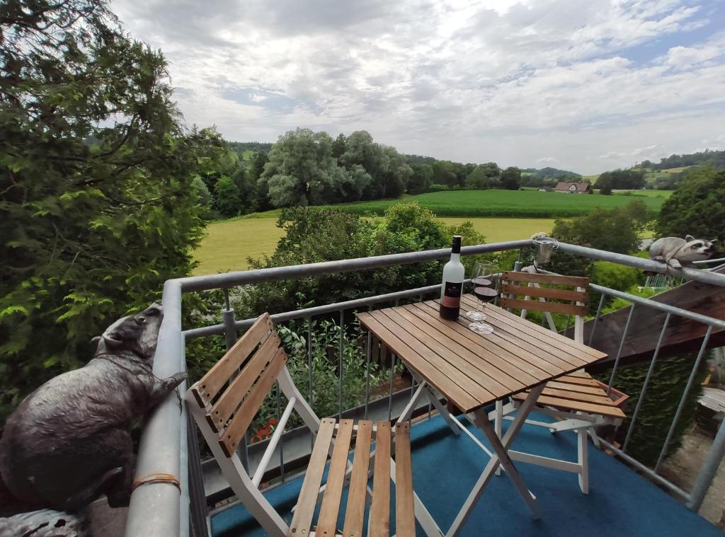 een terras met een tafel en twee stoelen en een fles wijn bij Ferienwohnung Hobbyhof Deggenhausertal in Deggenhausertal