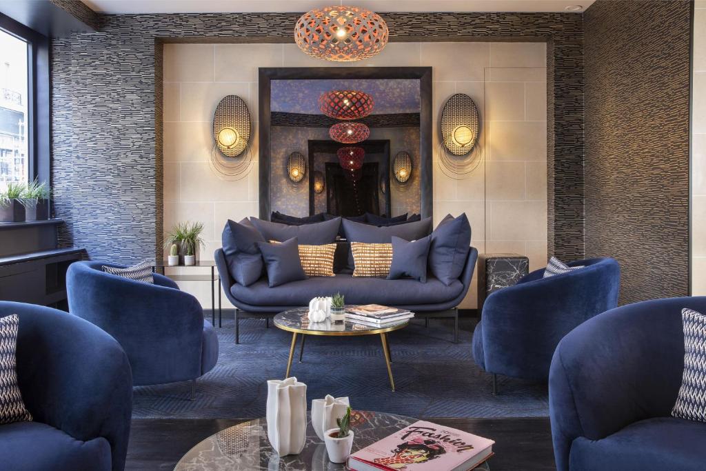 una sala de estar con sofás azules y una mesa. en Hôtel Elysées Régencia, en París