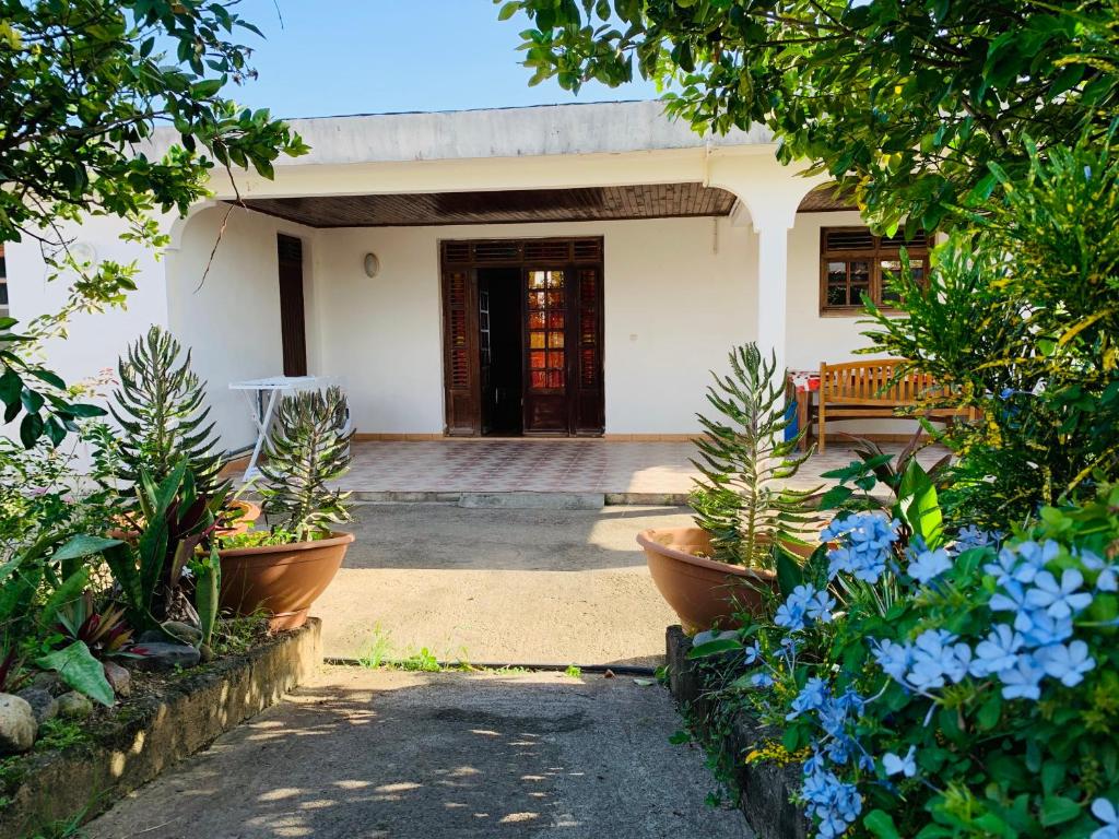 una casa con una puerta y algunas plantas y flores en The Kapokier, en Saint-Pierre