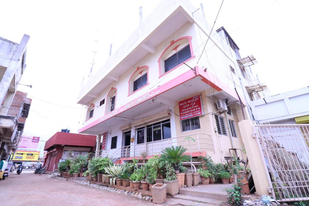 a white building with plants in front of it at Shanthi Comforts in Dāvangere