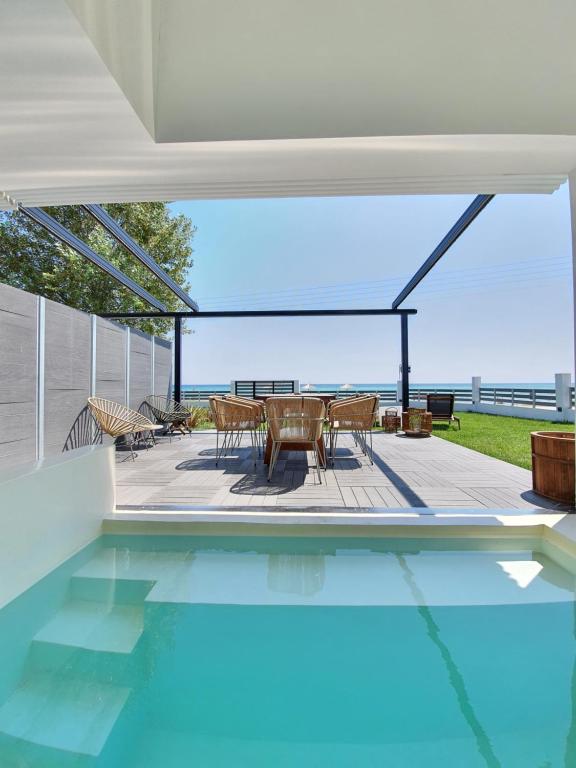 a swimming pool in a house with a table and chairs at Thea Suites in Nea Kalikratia