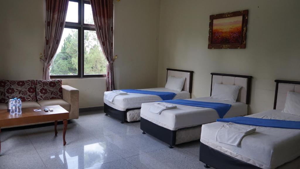 une chambre d'hôtel avec trois lits et un canapé dans l'établissement BRIA Hotel & Convention, à Bogor
