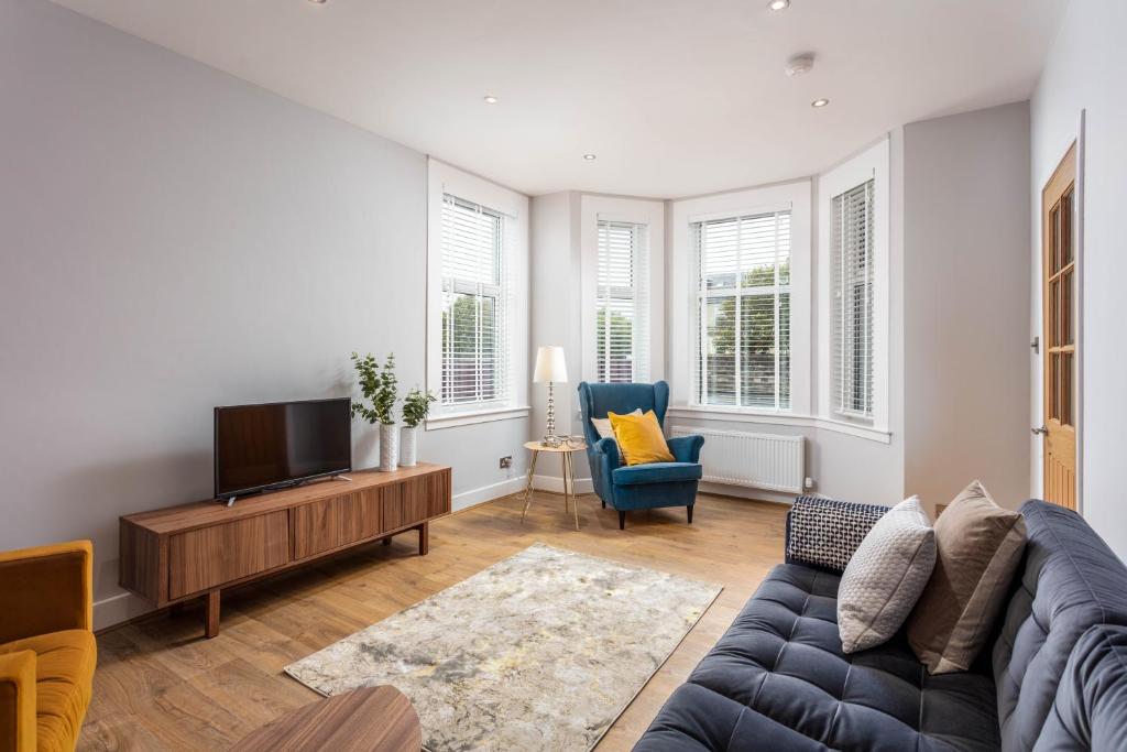 a living room with a couch and a tv at Seafield House - Donnini Apartments in Ayr