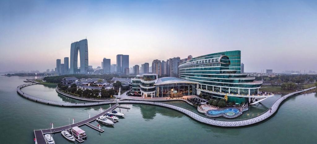 Crowne Plaza Suzhou, an IHG Hotel في سوتشو: مبنى كبير به مرسى به قوارب في الماء