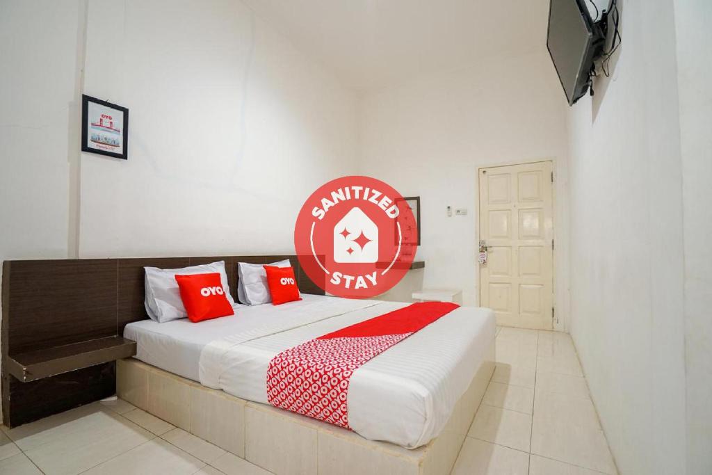 1 dormitorio con 1 cama grande con almohadas rojas en SUPER OYO 1868 Penginapan Sekip, en Palembang