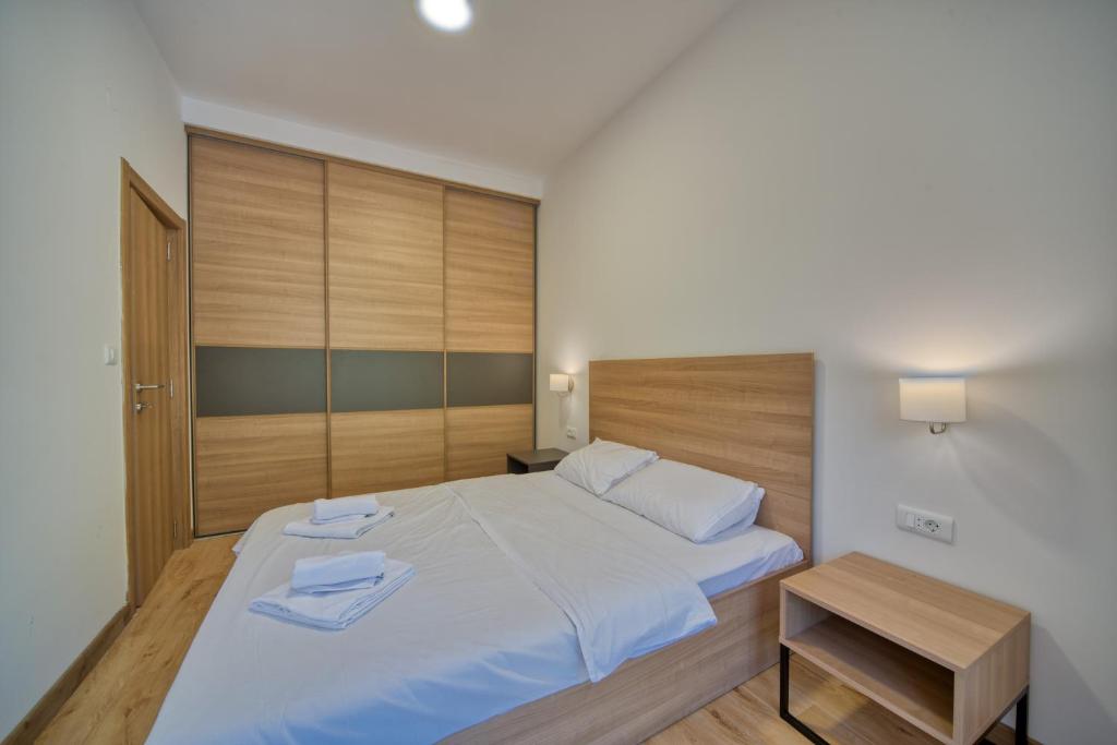 a bedroom with a large white bed with a wooden headboard at Trsteno Beach Apartments in Budva