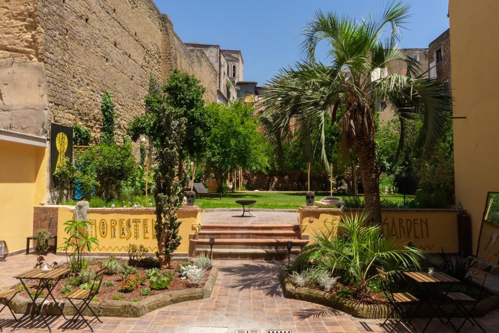 a courtyard with palm trees and a stone wall at HOPESTEL Secret Garden Napoli in Naples